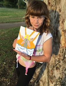 girl leaning against tree with painting